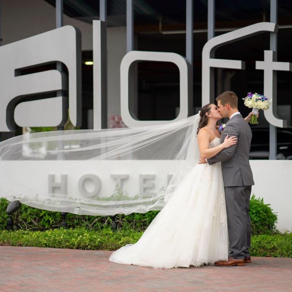 husband and wife kissing in front of hotel